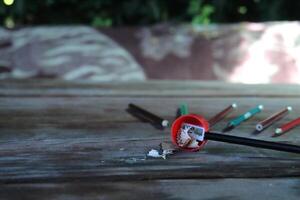 Black pencil in a red sharpener, shavings nearby. Space for text photo