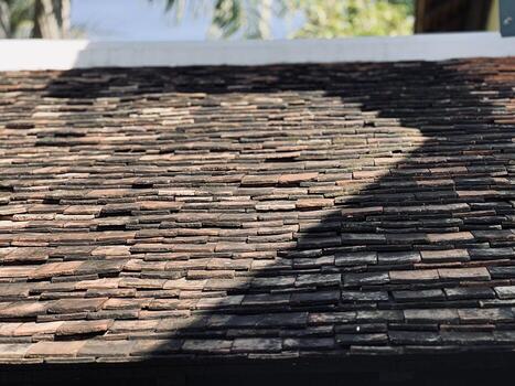 Traditional clay roof tiles cover a surface, displaying a worn, rustic texture in shades of brown and dark gray. photo