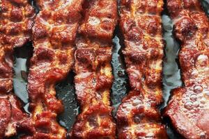 Bacon slice being cooked in frying pan. photo