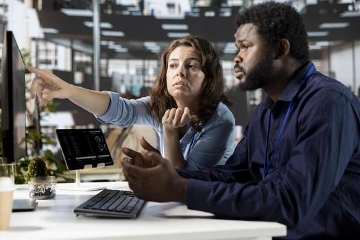 Young employee and manager gathered at the desk to examine data on pc, discussing objectives and strategizing solutions to solve administrative tasks. Aligning business goals and milestones. photo