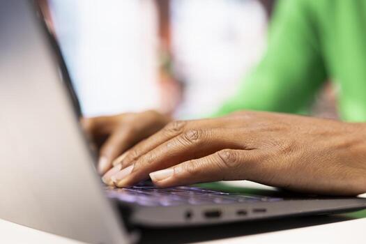 Freelancer in home office browsing internet on notebook, researching information online. Close up of teleworker typing on laptop keyboard, using search engine to find data relevant to work tasks photo