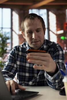 Man in apartment filling out online forms on laptop for loan, entering credit card details on internet website. Person typing on notebook at home, completing loan application forms photo