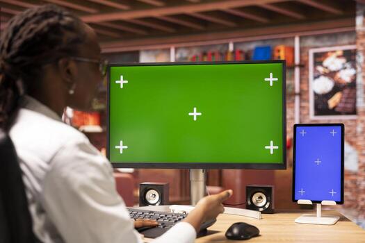 Student at home browsing internet on green screen computer and tablet, doing homework. Girl in apartment reading articles on chroma key PC and mockup device for school tasks photo