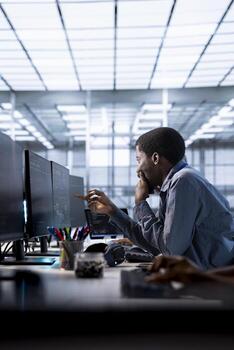 African american programmer doing checkup to prolong data center electronics life span and avoid downtime. IT worker in server room monitoring server infrastructure components using computer photo