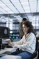 Woman working in high tech AI facility providing computing resources for different workloads. System administrator checking on artificial intelligence data center supercomputers photo