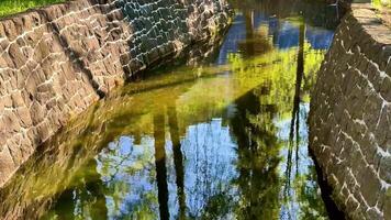 A serene park shows a stone wall by a stream, enhancing nature photo