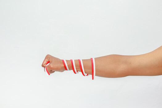 Arm wrapped in red and white ribbons against a plain background creating minimalist visual photo