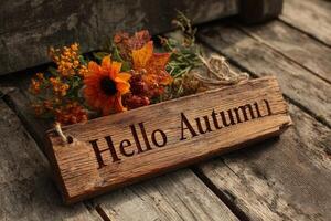 Welcome autumn with a rustic wooden sign adorned with seasonal flowers and leaves by a weathered wooden surface photo