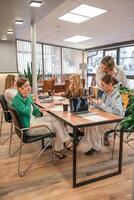 Businesswomen Meeting Laptops. Team collaborates at office table for strategy session, daytime work talk. photo