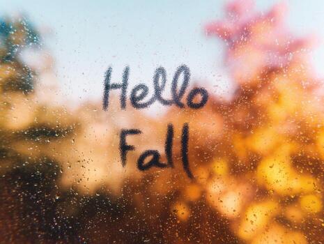 Autumn greeting. Handwritten hello fall on transparent window with warm colors photo