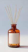 Amber glass bottle with reed diffuser sticks and blank label against a light background photo
