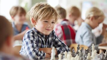 Young boy playing chess in classroom with other children, focused and cheerful photo