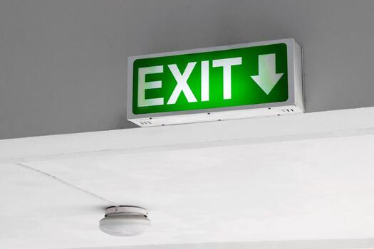 green emergency exit sign with downward arrow mounted on the ceiling, indicating evacuation route and safety precautions in building, emergency exit sign for indicating fire escape route and emergency photo