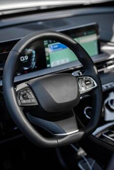 Close-up on steering wheel with integrated buttons and crisp digital dashboard, illuminated by natural daylight, digital dashboard displaying navigation and settings photo
