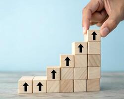 colorful Hand stacking wooden blocks with upward arrows creating a growth staircase isolated on white background photo