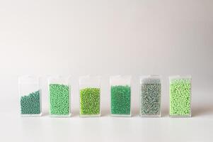 Set of transparent containers with green beads in gradients on white background photo