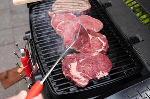 Grilling juicy steaks on outdoor barbecue grill with smoke rising in backyard photo