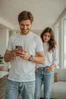 a cheerful man is texting someone on his smartphone, his sad wife next to him in the apartment photo
