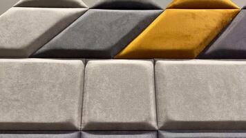 A wall of grey and yellow pillows with a triangle shape video