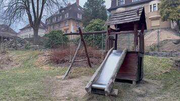 A wooden slide in a park with a house in the background video