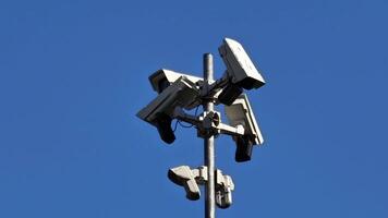 A collection of surveillance cameras strategically mounted on a tall pole, all capturing a clear view of the sky above video