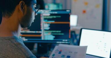 fechar-se jovem Ásia masculino digitando escrever pronto ai robô isto aplicativo inteligente programa nômade, jogo, terminal com codificação linguagem, desenhista, grande dados Centro em Área de Trabalho computador dentro noite escritório. video