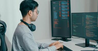 jovem adulto Ásia masculino freelance Óculos digitando escrever pronto ai robô isto aplicativo inteligente programa nômade, jogo, terminal com codificação, do utilizador interface, desenhista, grande dados Centro em Área de Trabalho computador video