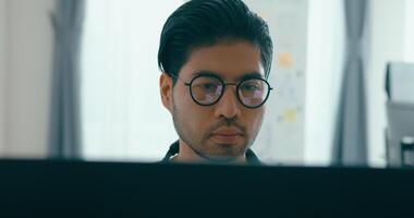 närbild ung Asien manlig frilans glasögon skriver skriva prompt ai bot den app program nomad, spel, terminal med kodning, användare gränssnitt, designer, stor data Centrum på skrivbordet dator. video