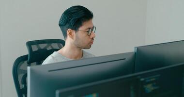 jovem Ásia masculino freelance Óculos digitando escrever pronto ai robô isto aplicativo inteligente programa nômade, jogo, terminal com codificação, do utilizador interface, desenhista, grande dados Centro em Área de Trabalho computador. video