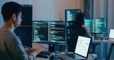 gruppo Asia maschio, femmina libero professionista digitando Scrivi richiesta ai Bot esso App inteligente programma nomade, gioco, terminale con codifica linguaggio, progettista, grande dati centro su del desktop computer nel notte ufficio. video