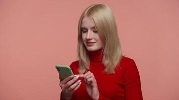 Excited woman reacting to message on smartphone on pink video