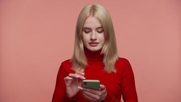 Woman scrolling on smartphone against pink background video