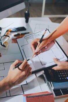 Two people working on a blueprint with a computer photo