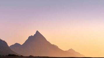 Mountain peak silhouette at sunset with soft pastel sky and misty atmosphere creating calm and peaceful mood photo