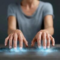 Person typing on futuristic glowing virtual keyboard with hands focused, showing technology and innovation in modern setting photo