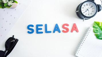 Flat lay composition with red and blue color foam letters spelling word tuesday in Indonesian, SELASA isolated on white background photo