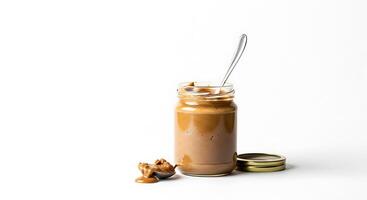 Jar of creamy peanut butter with a spoon and peanuts photo