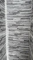 Interior corner showcases a gray textured stone wall with horizontal brickwork creating a modern aesthetic photo