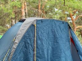 Blue camping tent pitched in a forest campsite, embracing outdoor adventure photo