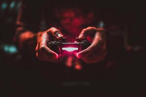Gamer hand holding illuminated game controller in dark room, focused and intense atmosphere photo
