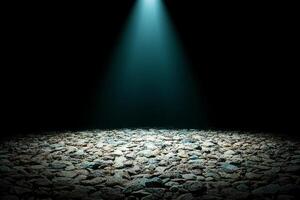 A dark room with a spotlight shining on a gravel floor photo