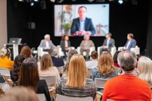 Audience attending hybrid conference with speakers and online presenter photo