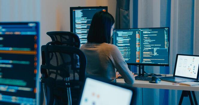 Young Asia female freelance eyeglasses typing write prompt AI bot IT app smart program nomad, game, terminal with coding language, designer, big data center on desktop computer in night office. photo