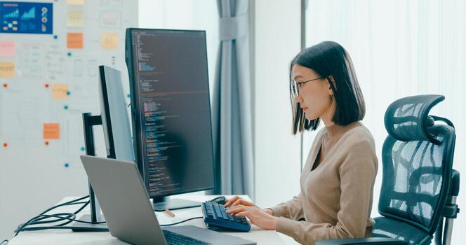 Young Asia female freelance eyeglasses typing write prompt AI bot IT app smart program nomad, game, terminal with coding, user interface, big data center on desktop computer photo