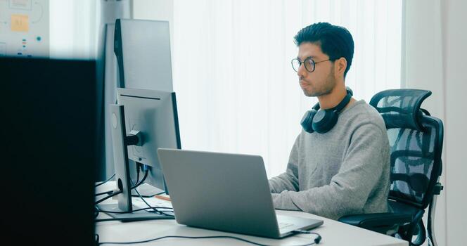 adult Asia male freelance typing write prompt AI bot IT app smart program nomad, game, terminal with coding, user interface, designer, big data center on desktop computer. photo