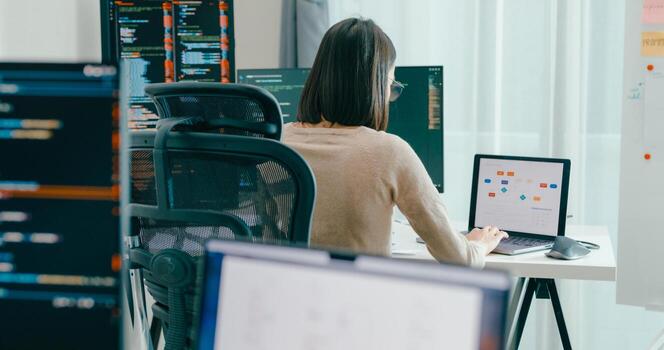 Young Asia female freelance eyeglasses typing write prompt AI bot IT app smart program nomad, game, terminal with coding, user interface, designer, big data center on desktop computer. photo