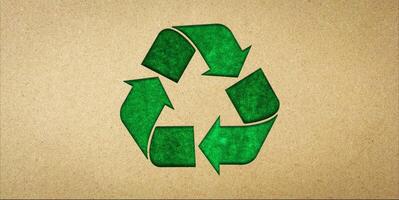 Green recycling symbol on brown paper. Concepts of reducing waste and reusing, symbolism of environmentally friendly products, CSR, zero waste. photo
