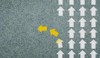Concept of different business and decisions. Yellow arrow crossing direction, white arrow on asphalt road. With copy space. photo