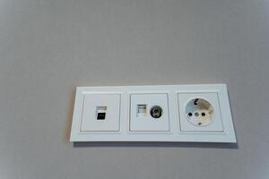 This image features a detailed close up view of a white electrical outlet that is mounted on a surface of a wall, providing access to AC power and electricity in the room photo