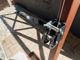 This image features a detailed close up of a heavyduty winch that is mounted securely on a sturdy wooden post, highlighting the intricate design and functionality of this mechanical device photo